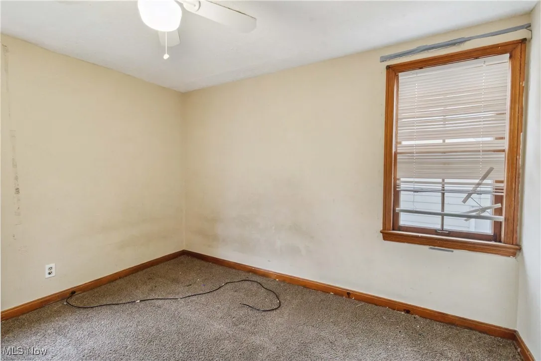 Carpeted spare room featuring a ceiling fan and baseboards