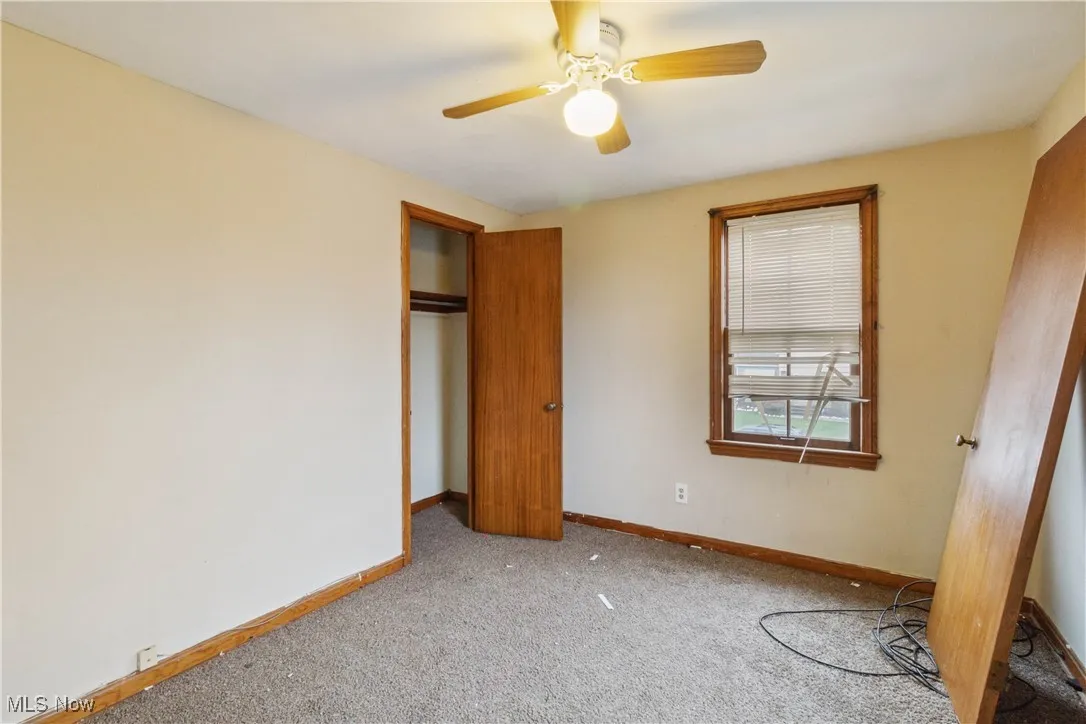 Unfurnished bedroom featuring a closet, carpet flooring, baseboards, and ceiling fan