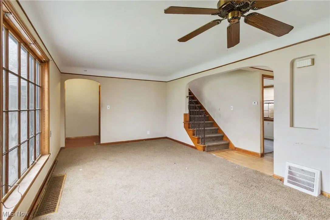 Empty room featuring carpet, baseboards, visible vents, and arched walkways