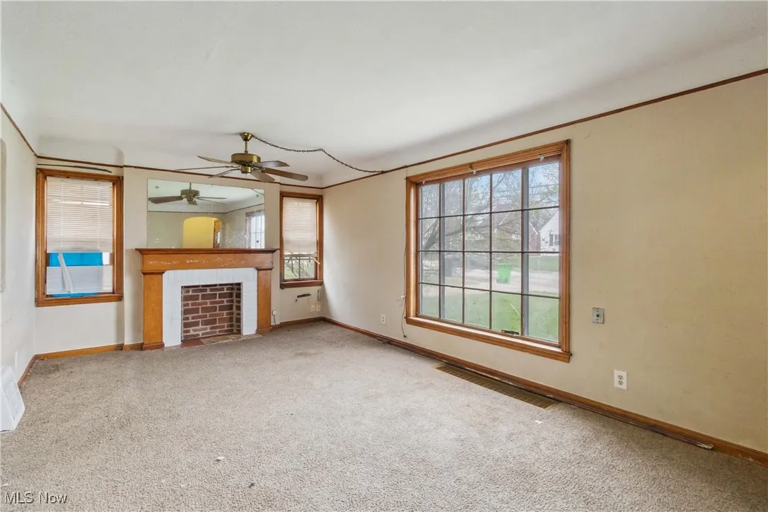 Unfurnished living room featuring carpet, baseboards, and a wealth of natural light