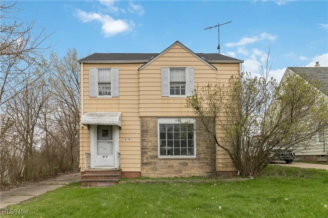 View of front of home featuring entry steps, stone siding, and a front lawn
