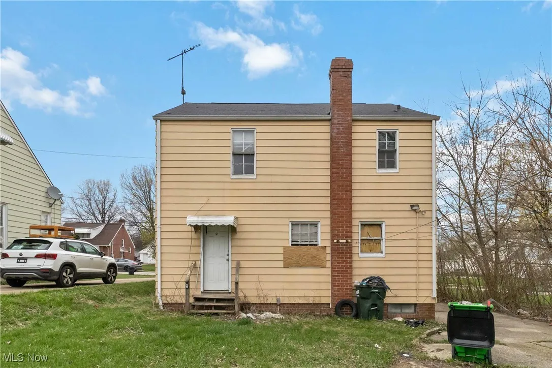 Rear view of property with a lawn, a chimney, and entry steps