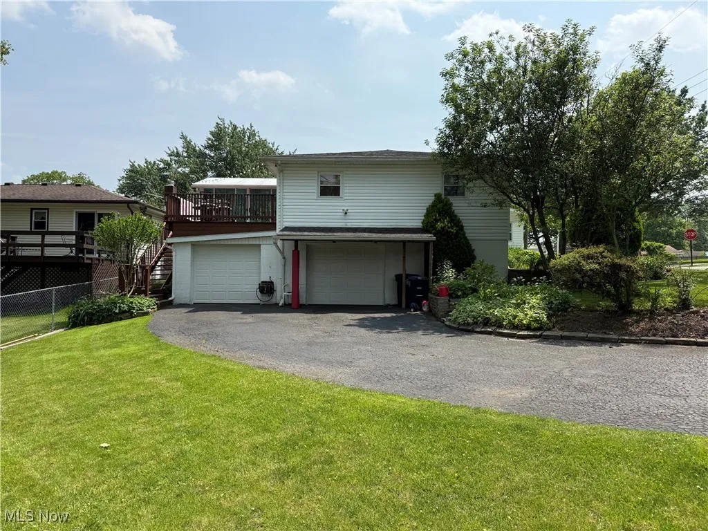 View of front of house with an attached garage, driveway, and a deck