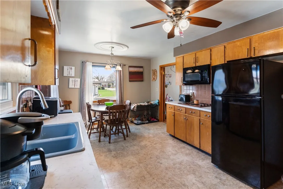 Kitchen with light countertops, tasteful backsplash, a ceiling fan, and black appliances