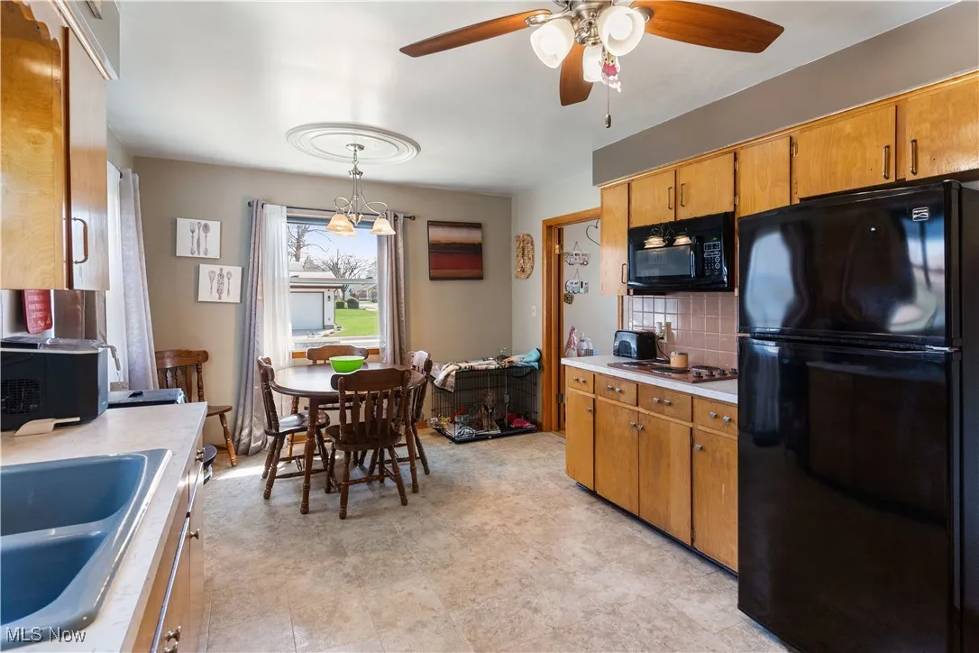 Kitchen featuring a sink, black appliances, decorative backsplash, ceiling fan, and light countertops