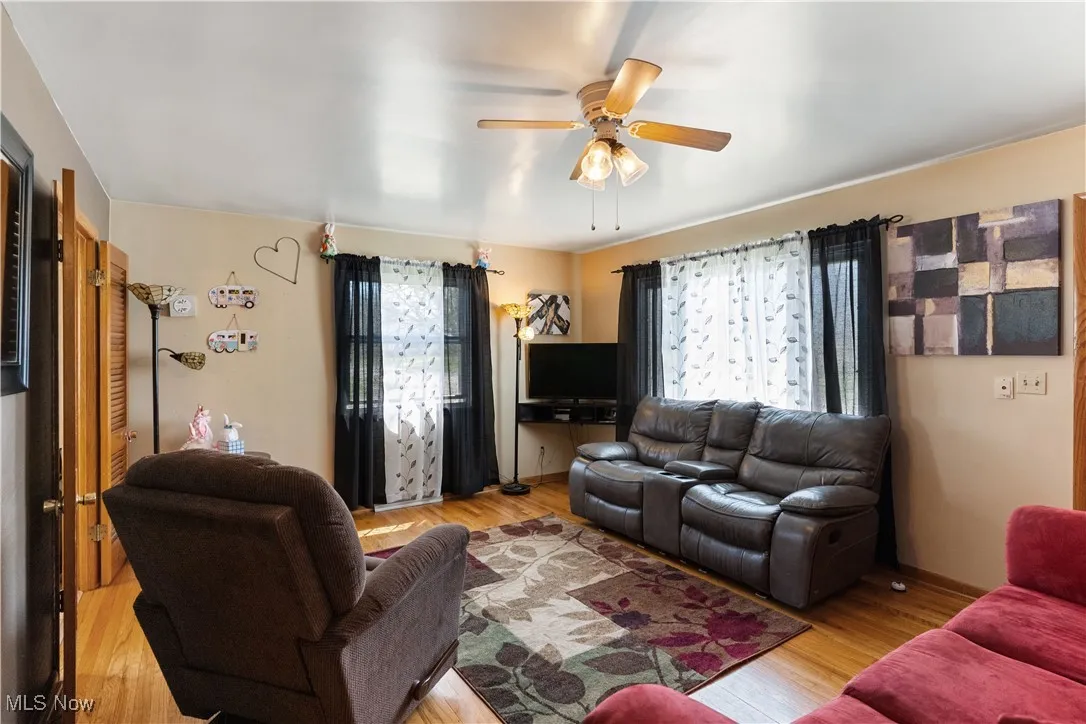 Living area with wood finished floors, a healthy amount of sunlight, and a ceiling fan