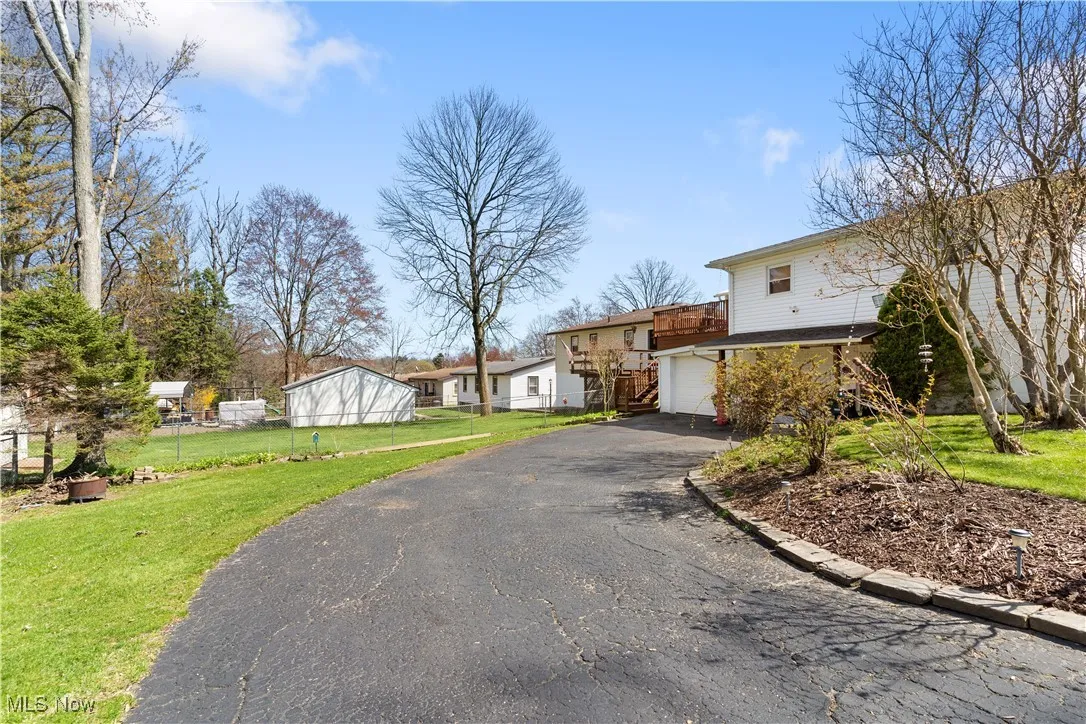View of front of home with fence, a front lawn, and aphalt driveway