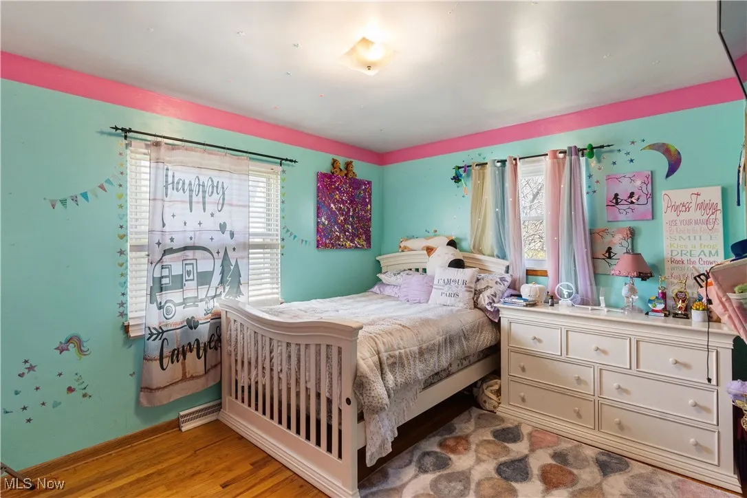 Bedroom with baseboards, wood finished floors, and multiple windows