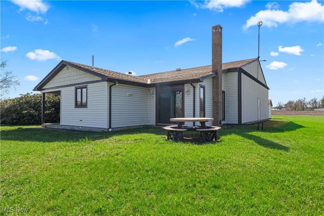 Front and side of property featuring a yard and a shingled roof.  Hangar door/wall down