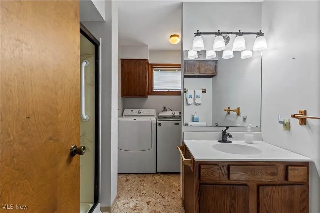 Bathroom with a shower stall, vanity, and washing machine and clothes dryer