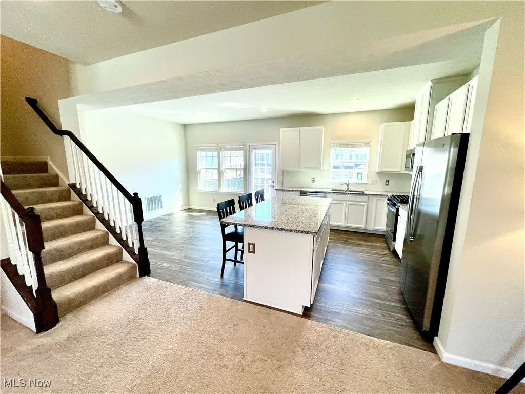 Kitchen featuring stainless steel appliances, a kitchen bar, white cabinets, visible vents, and a kitchen island