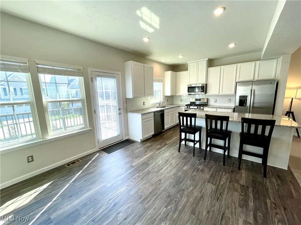 Kitchen with stainless steel appliances, visible vents, a sink, and dark wood-style flooring