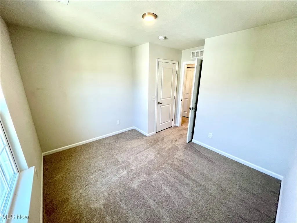 Unfurnished bedroom featuring baseboards, visible vents, and carpet