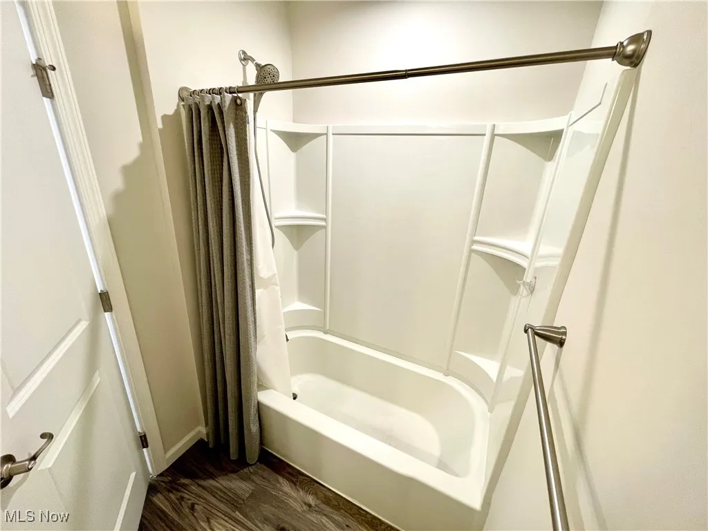 Bathroom with shower / bath combo with shower curtain and wood finished floors