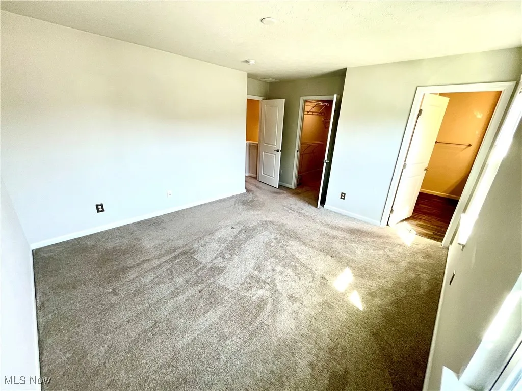 Unfurnished bedroom with a closet, carpet floors, a spacious closet, and baseboards