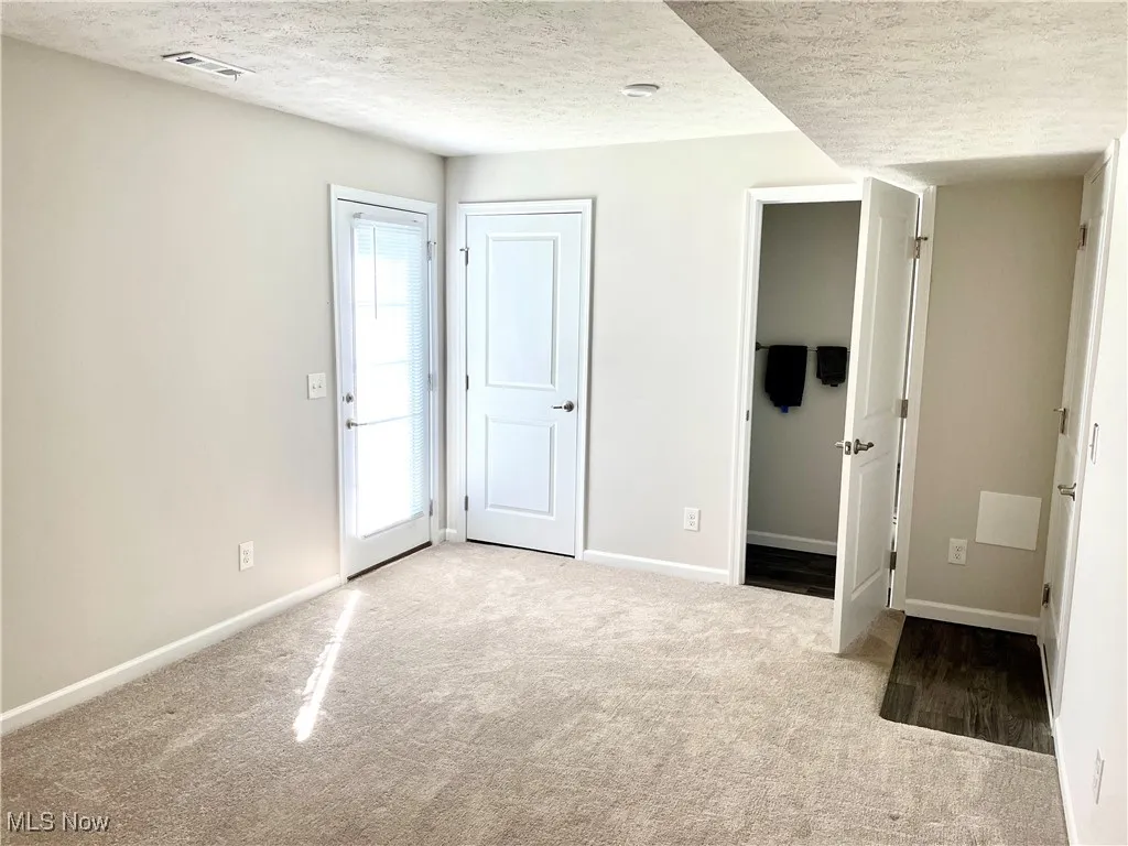 Unfurnished bedroom with baseboards, carpet flooring, a textured ceiling, and visible vents