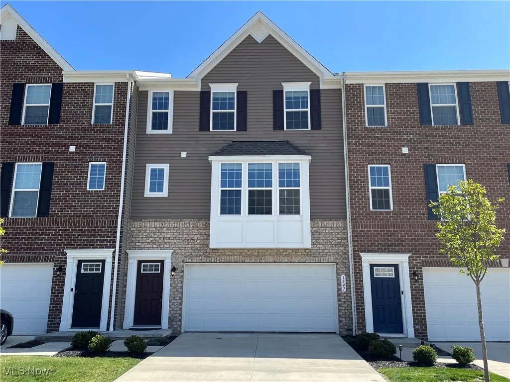 Townhome / multi-family property featuring brick siding, driveway, and a garage