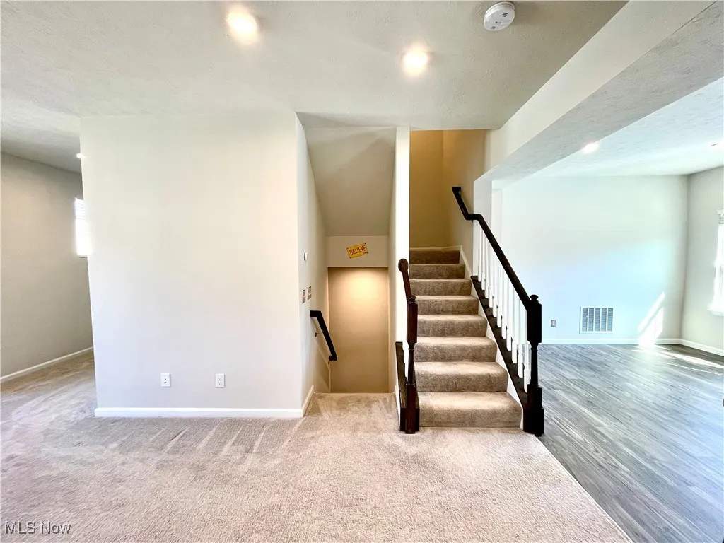 Stairway with baseboards, visible vents, and carpet flooring