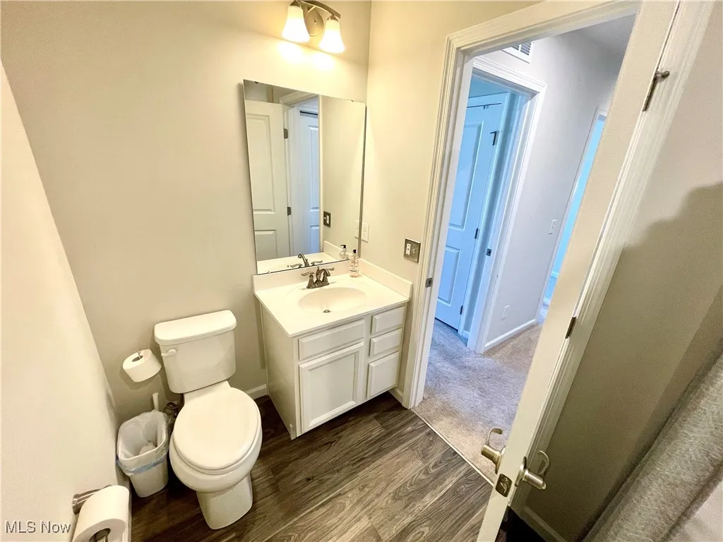 Bathroom featuring wood finished floors, toilet, and vanity