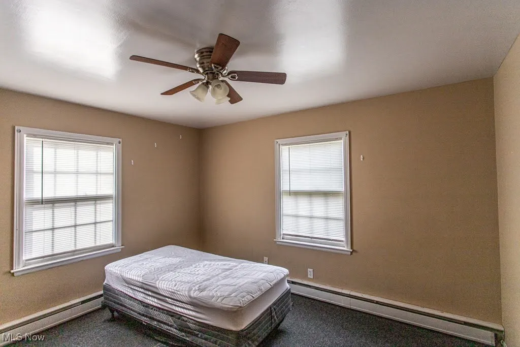 Bedroom with carpet, baseboard heating, and multiple windows