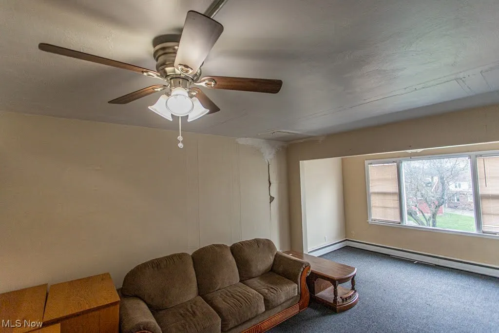 Carpeted living area with a baseboard radiator, baseboards, and ceiling fan