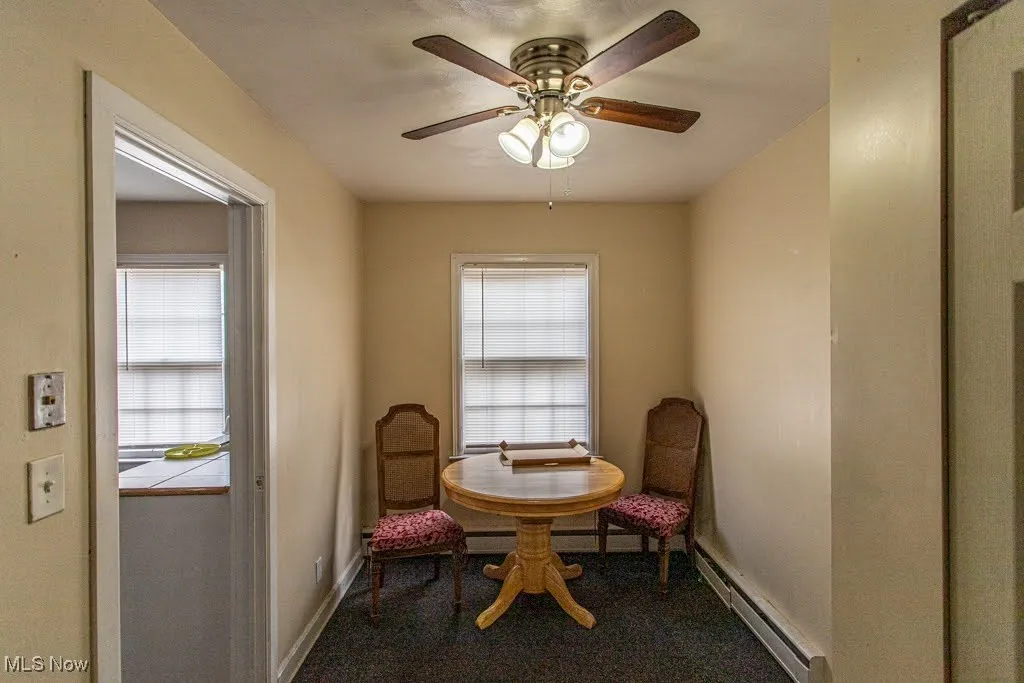 Living area featuring carpet floors, ceiling fan, a baseboard heating unit, and a healthy amount of sunlight