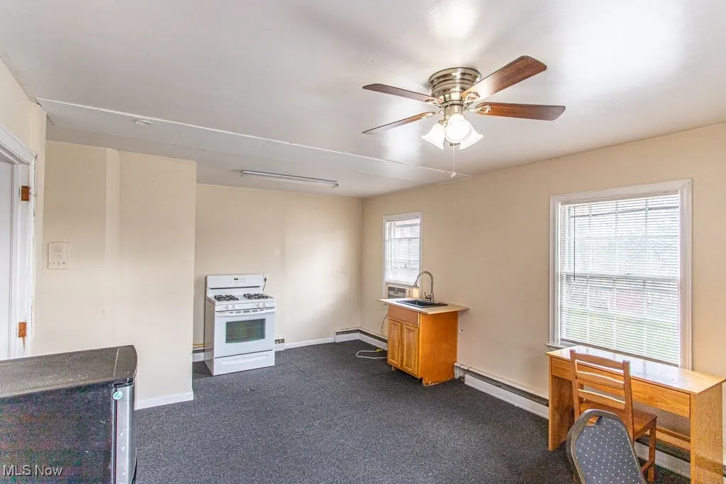 Kitchen with baseboard heating, baseboards, gas range gas stove, ceiling fan, and a sink