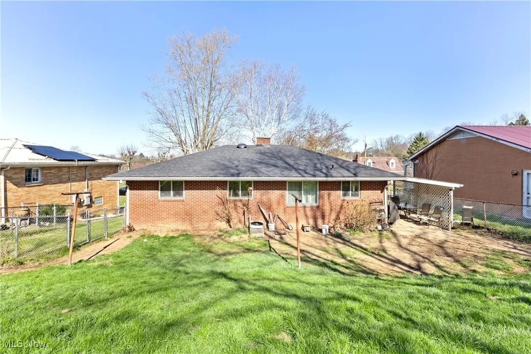 Back of property featuring brick siding, a yard, a chimney, and a fenced backyard