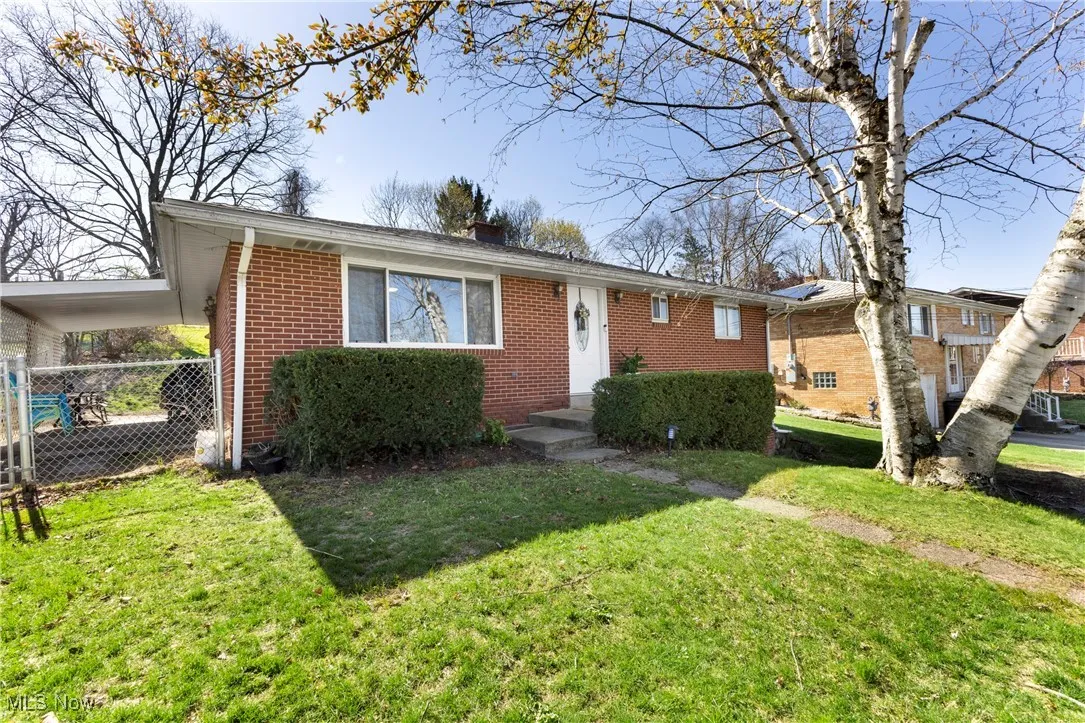 View of front of home with fence, a front lawn, brick siding, and a chimney