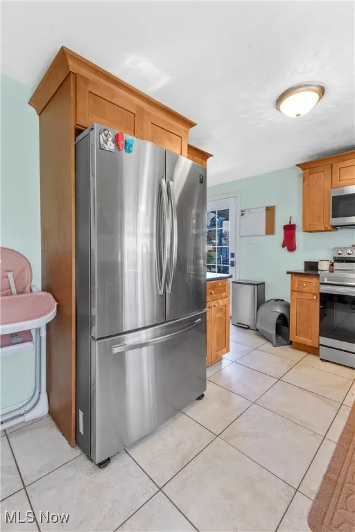 Kitchen featuring brown cabinets, appliances with stainless steel finishes, and light tile patterned floors