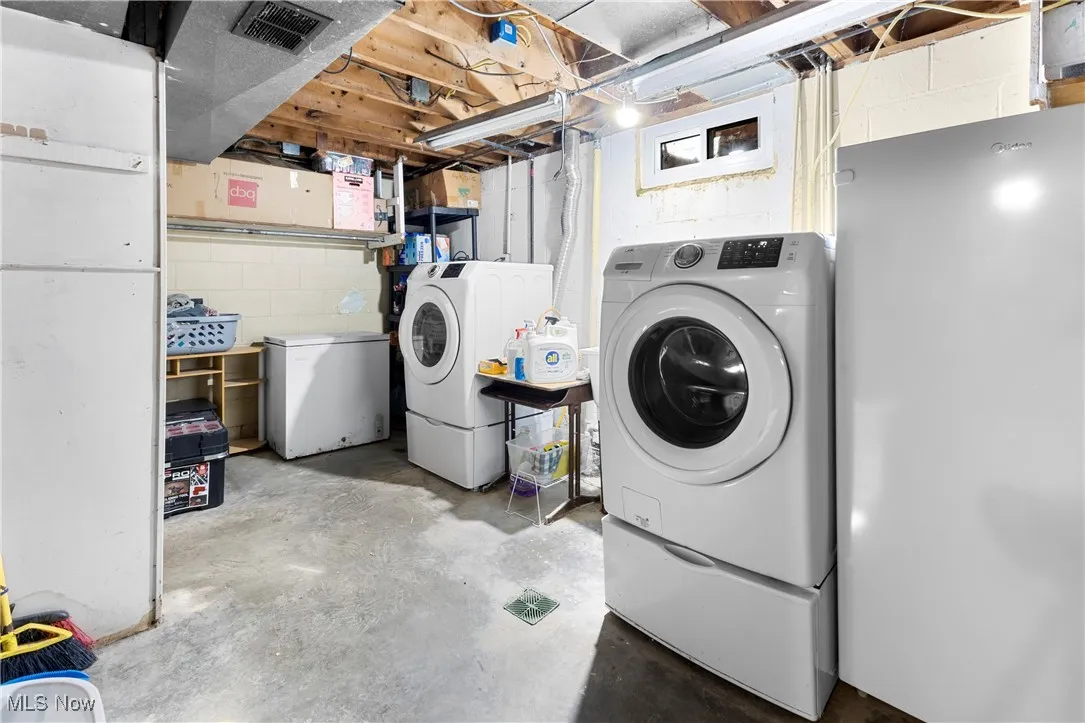 Clothes washing area featuring independent washer and dryer, visible vents, and laundry area