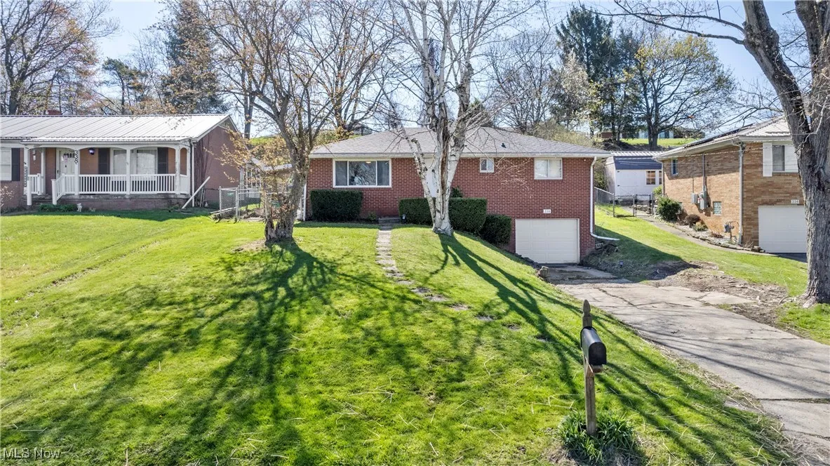 Ranch-style home with driveway, a porch, brick siding, a front yard, and a garage