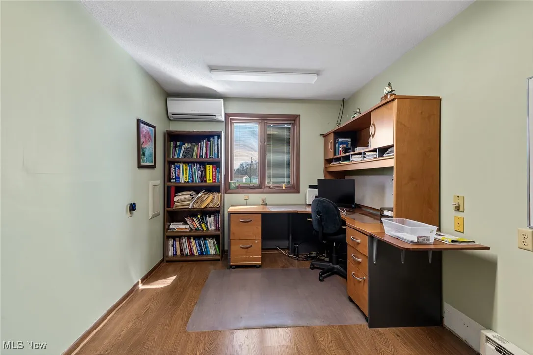Office featuring baseboards, dark wood-style flooring, an AC wall unit, a textured ceiling, and a baseboard heating unit