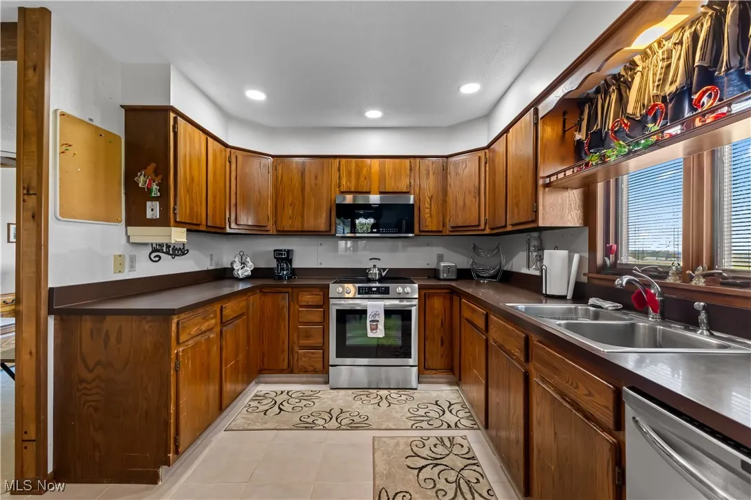 Kitchen featuring dark countertops, a sink, brown cabinets, and appliances with stainless steel finishes