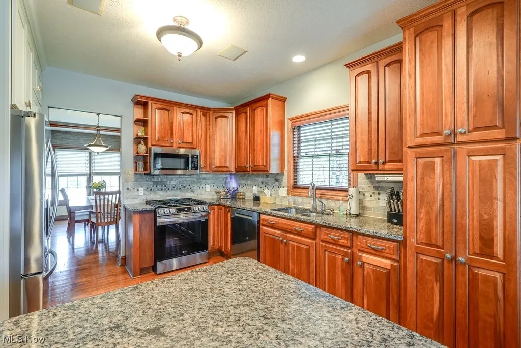 Fully applianced kitchen with island, granite countertops, wood floors, and 2 large pantry cabinets connected to dining room and dinette