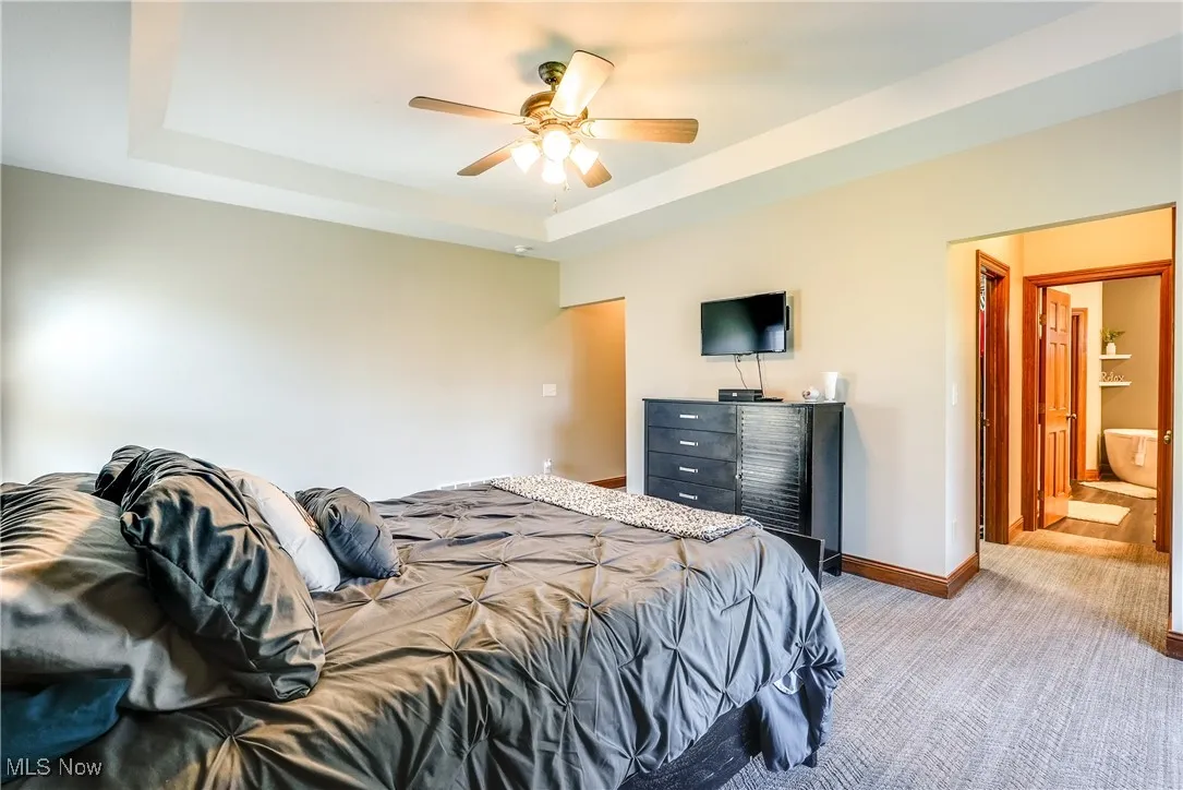 Large 1st floor primary bedroom with tray ceiling, newer carpet, and leads to large walk-in closet and beautifully updated en-suite bath.