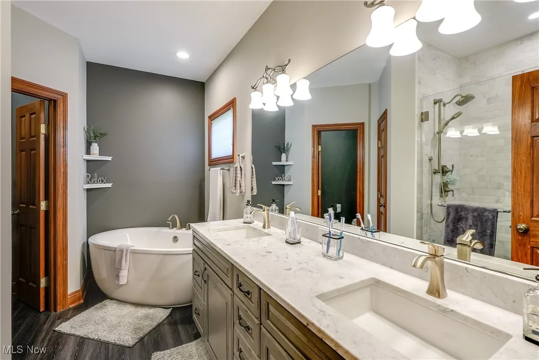 Beautifully updated primary bath with large soaking tub, double vanity, and large walk-in marble shower with bench and separate toilet room.