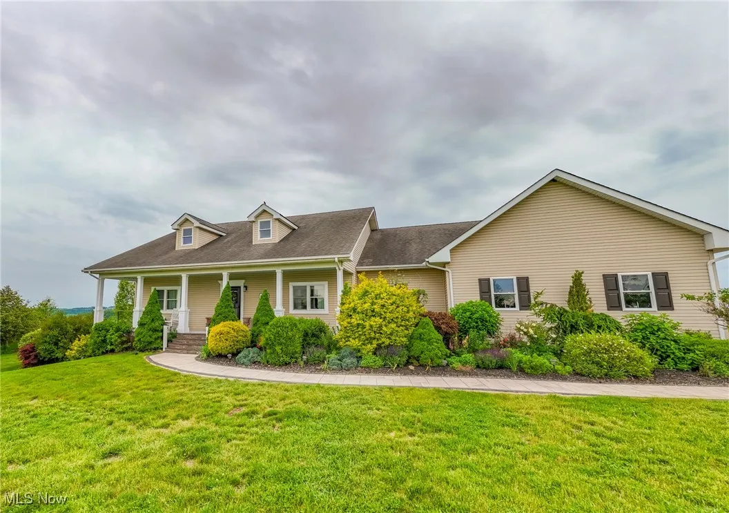 New england style home featuring a front lawn, a porch, and a shingled roof