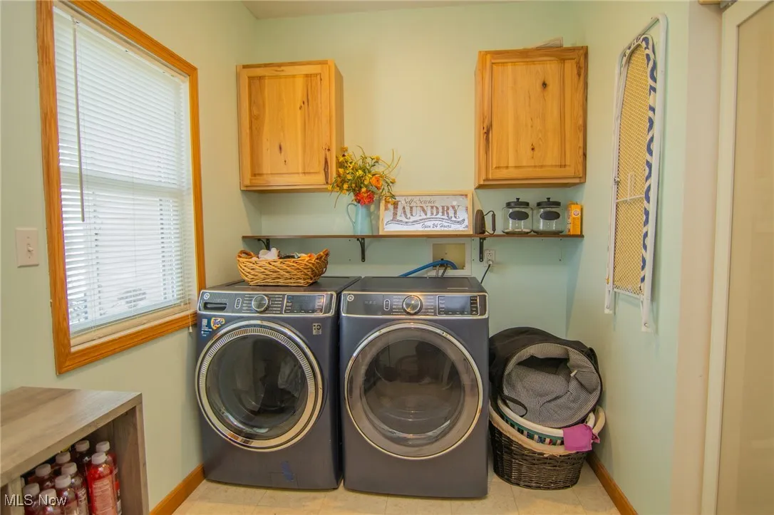 Washroom with baseboards, independent washer and dryer, and cabinet space