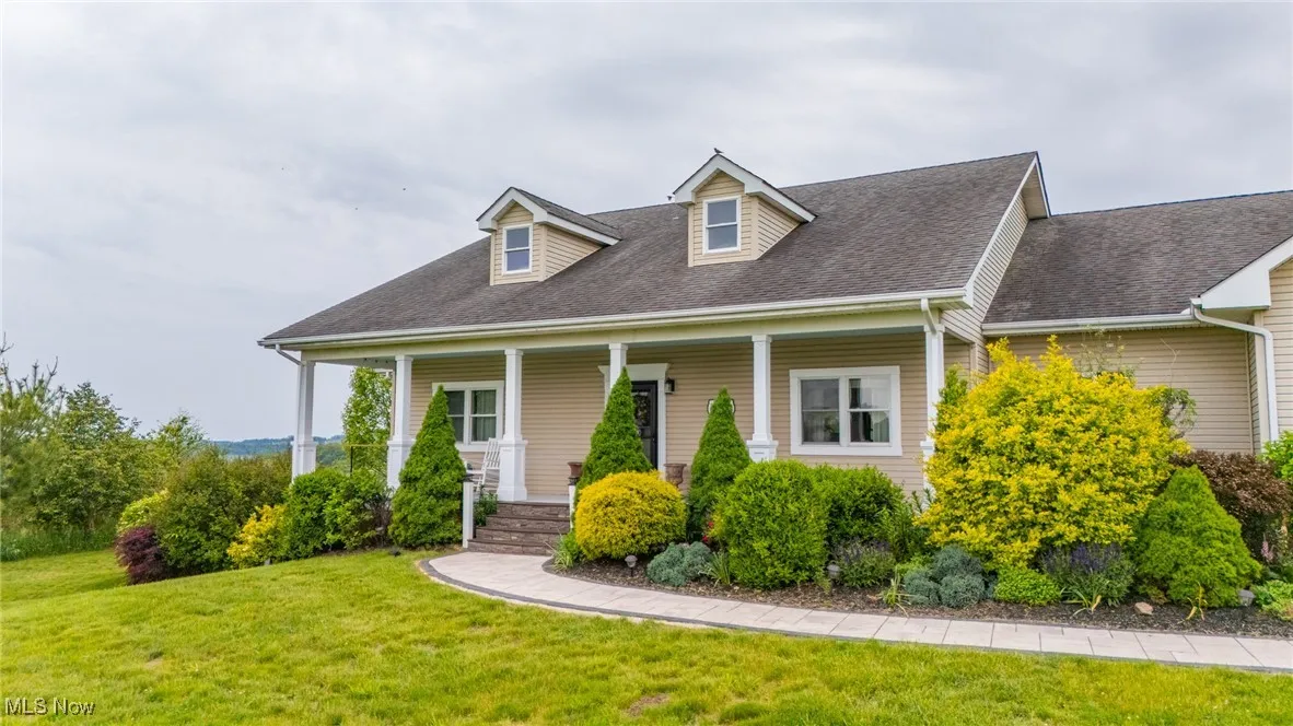 Cape cod-style house featuring covered porch, a front yard, and a shingled roof