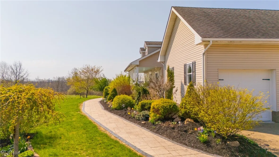 View of property exterior with an attached garage, roof with shingles, and a lawn