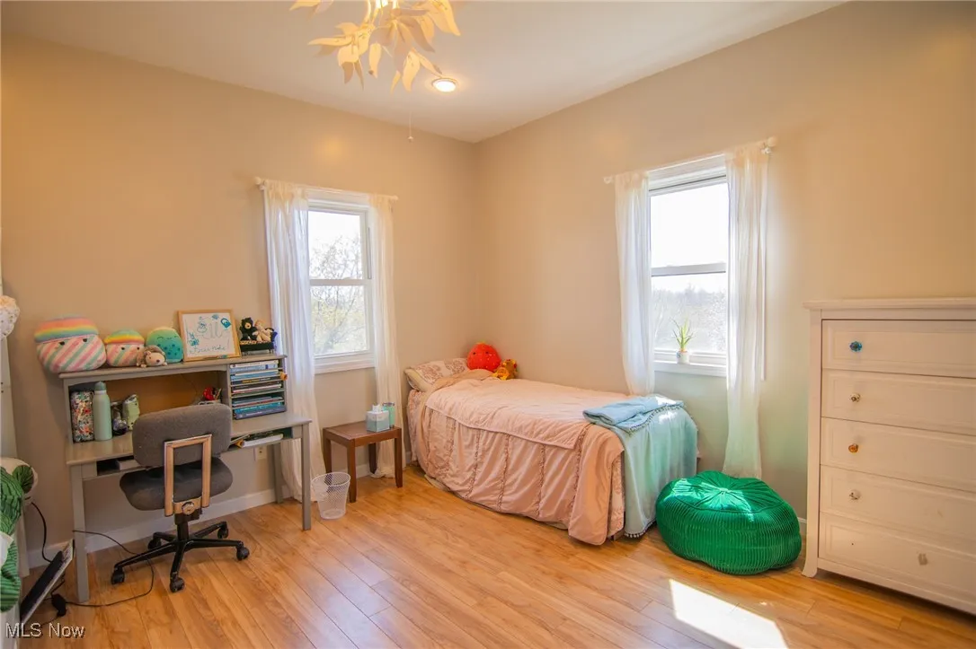 Bedroom with wood finished floors and multiple windows