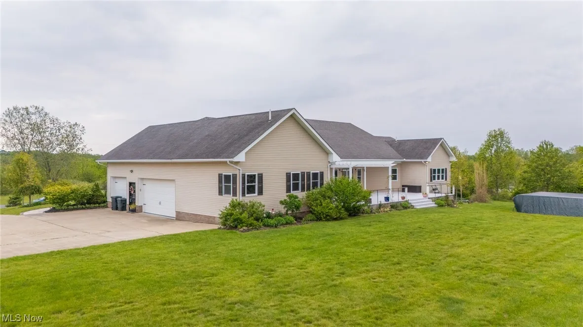 Back of property featuring driveway, a garage, and a yard