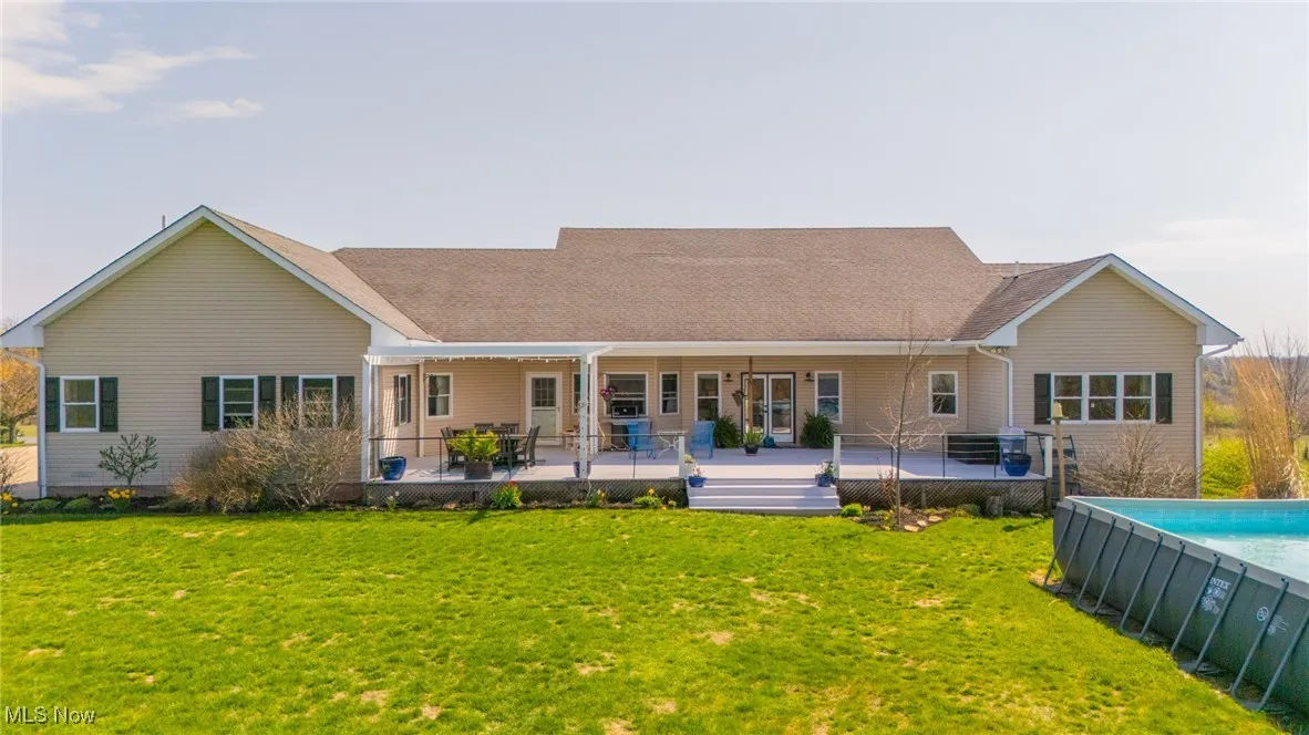 Rear view of house with a patio area, a lawn, and an outdoor pool