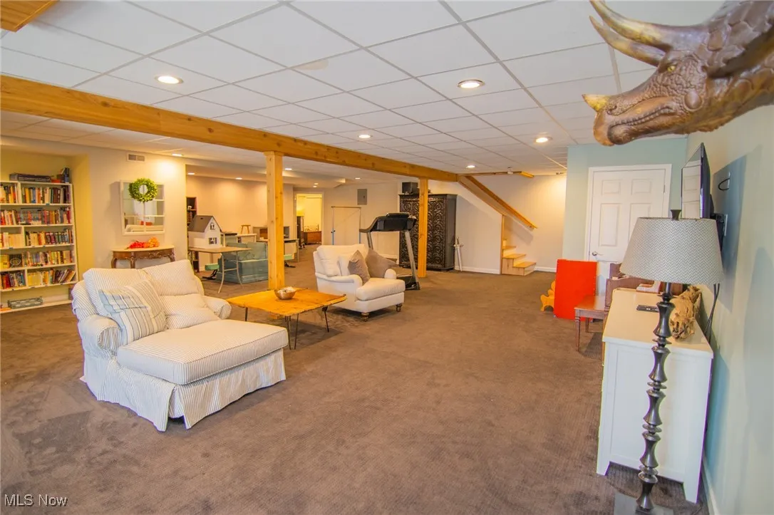 Carpeted living area with recessed lighting, a paneled ceiling, visible vents, and stairs