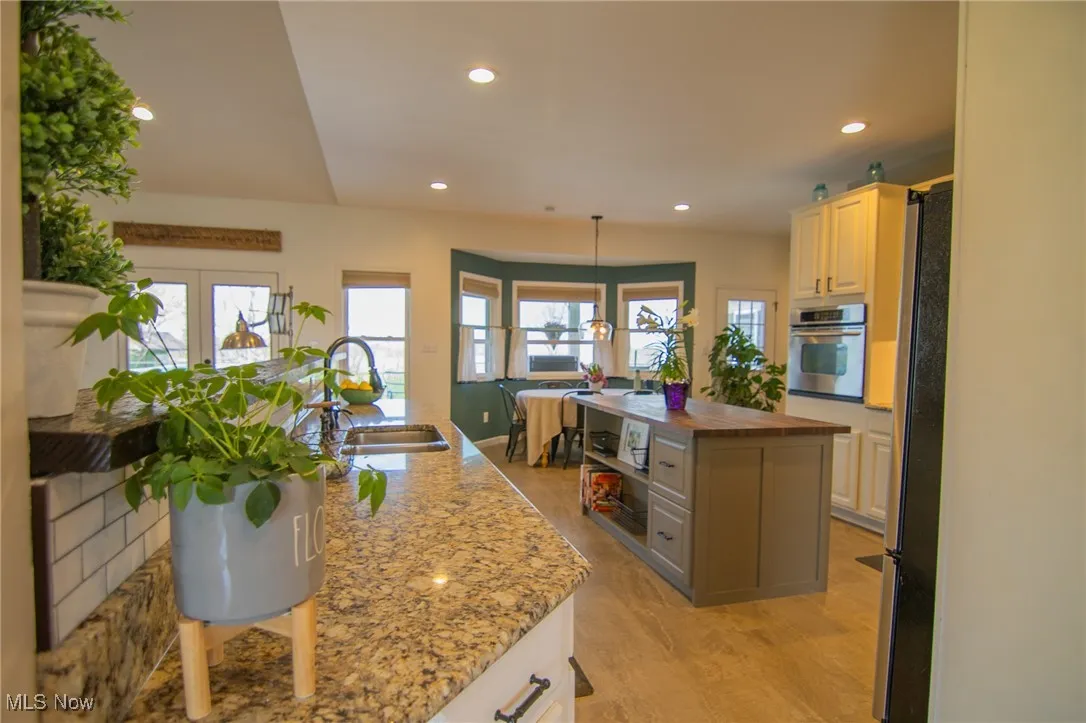 Kitchen featuring a sink, recessed lighting, butcher block countertops, a kitchen island, and appliances with stainless steel finishes
