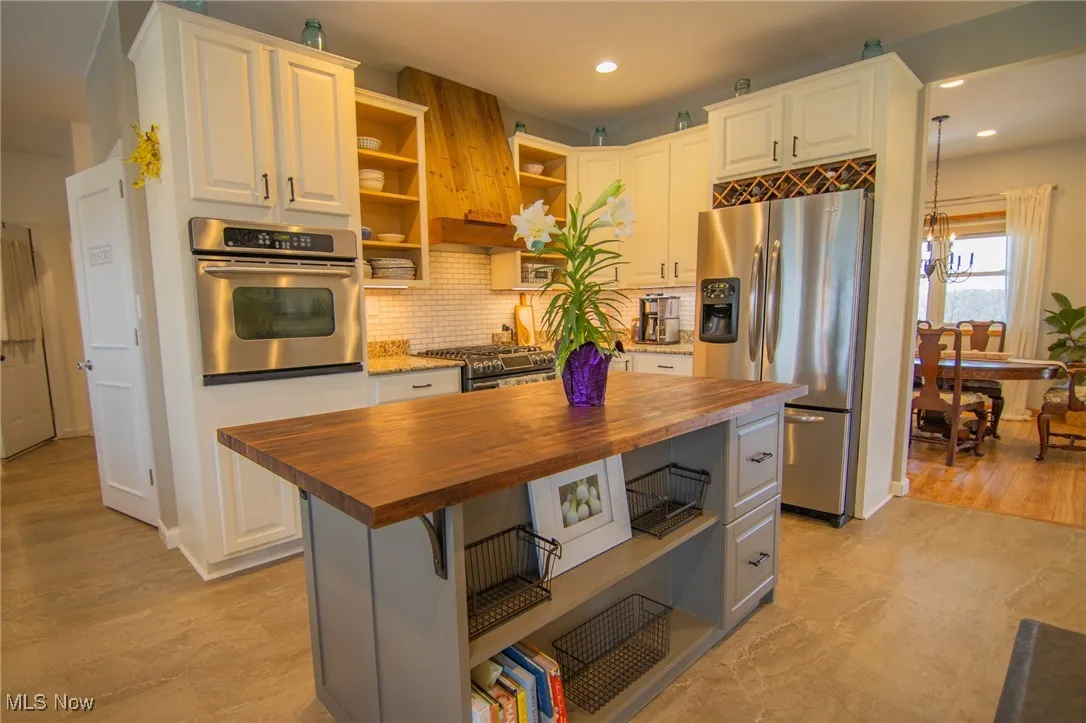 Kitchen featuring wood counters, open shelves, stainless steel appliances, and recessed lighting