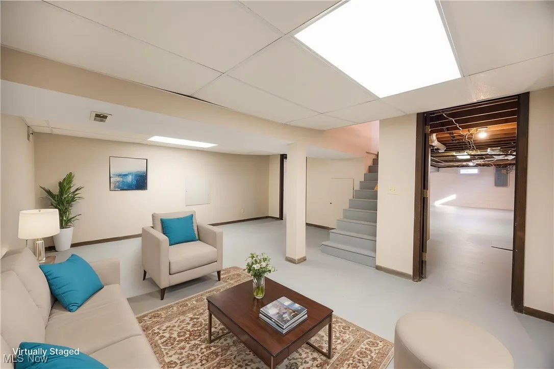 Virtually staged lower level room area featuring a paneled ceiling and stairway