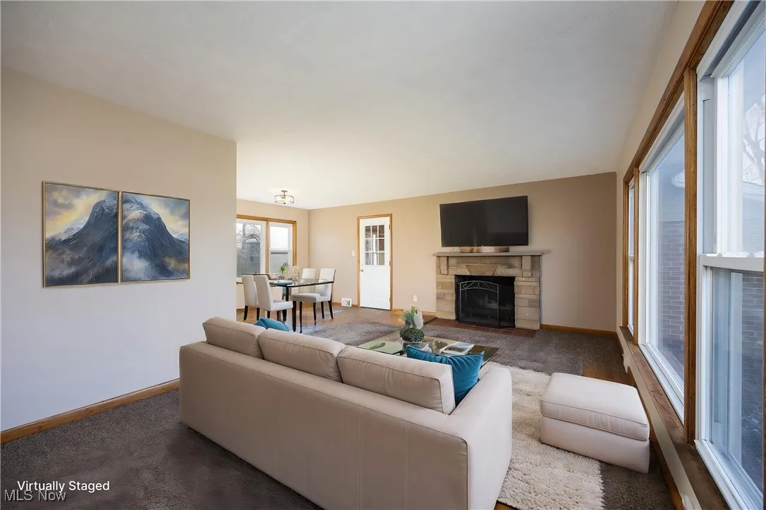 Virtually staged living area with carpet, baseboards, and a fireplace