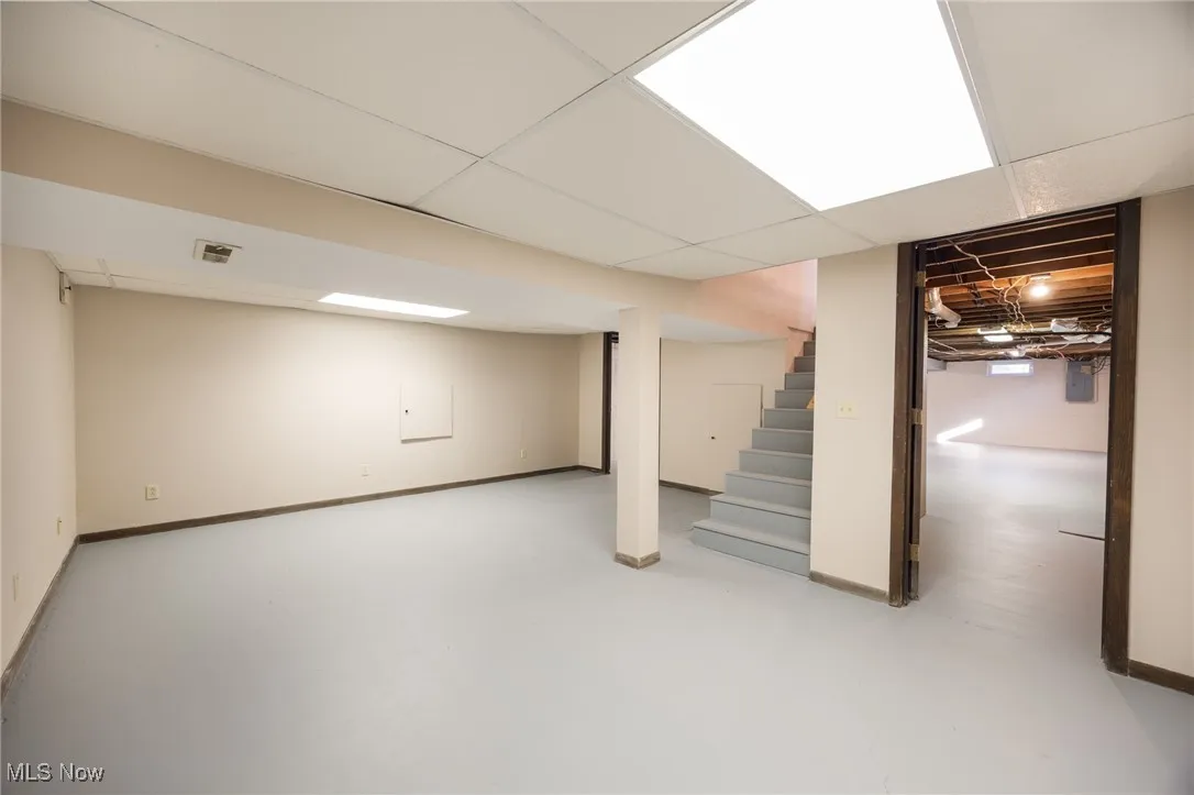 Finished basement with baseboards, a drop ceiling, and stairs